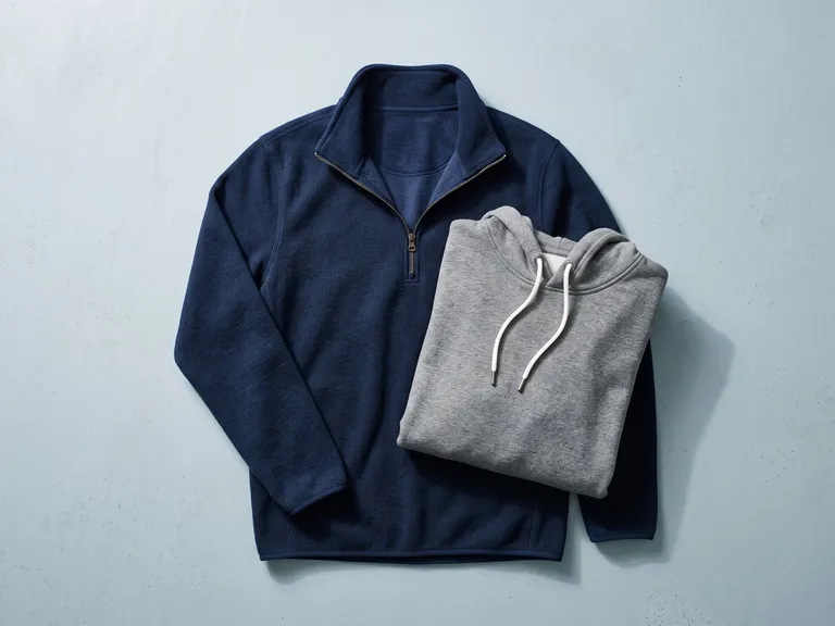 Felpa blu con mezza zip e pile grigio con cappuccio, piegati uno sull’altro