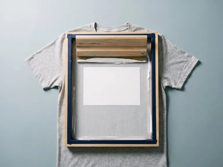 T-shirt grigia sotto un telaio serigrafico per la stampa del logo