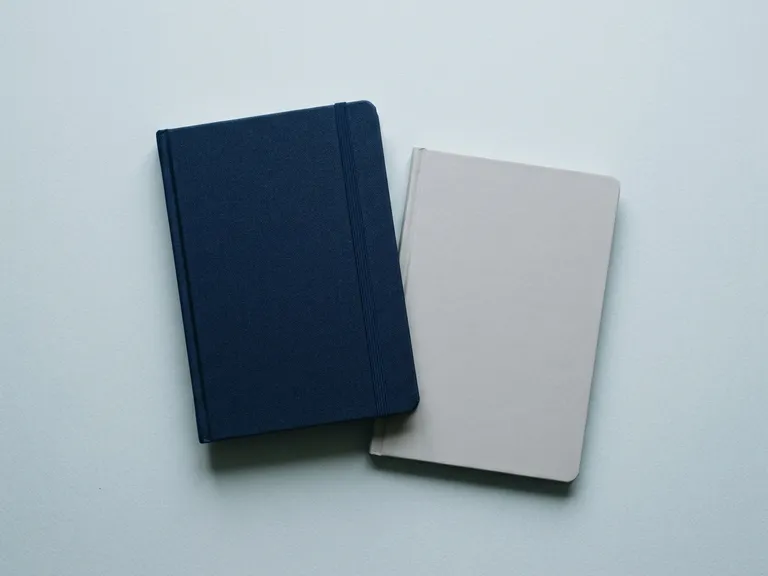 Due quaderni con copertina rigida, blu e grigio, con elastico